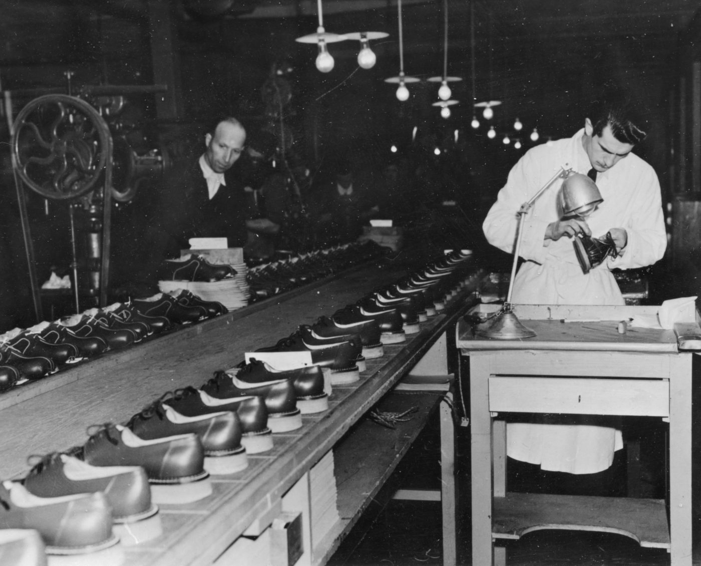 Ouvriers au travail et rangées de chaussures sur une chaîne de fabrication française après la Seconde Guerre mondiale