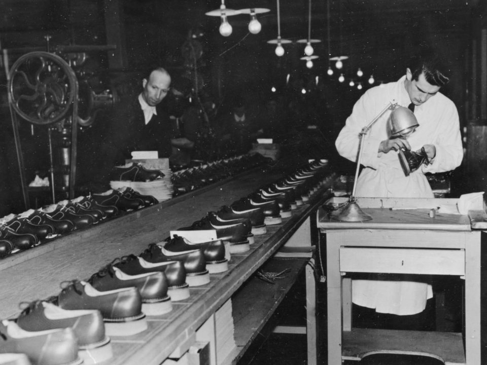 Ouvriers au travail et rangées de chaussures sur une chaîne de fabrication française après la Seconde Guerre mondiale